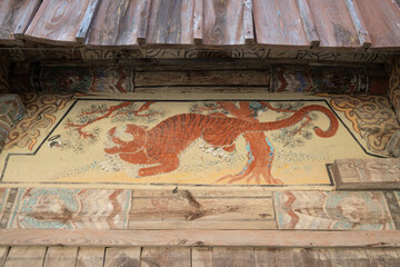 Traditional Korean folk painting of a tiger and pine tree on the wooden wall of a Buddhist temple © joeun