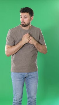 Adult man stands against green screen, touching head and looking puzzled, she forgot something important