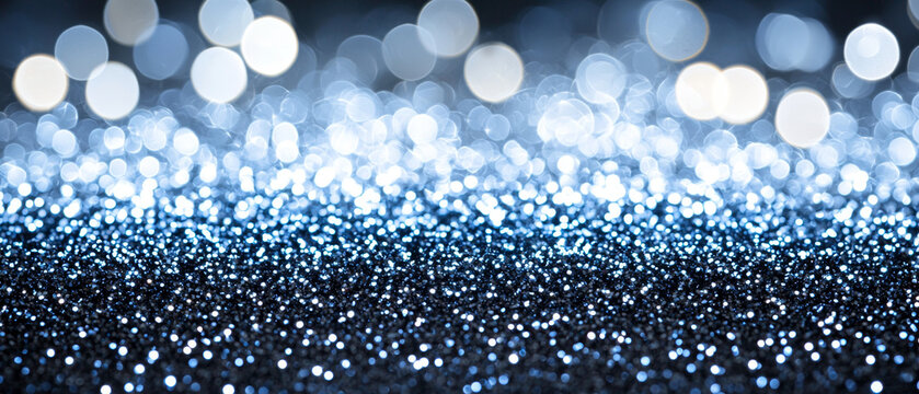 Blue glitter foreground with countless sparkling particles, transitioning to soft, luminous bokeh circles in the abstract background