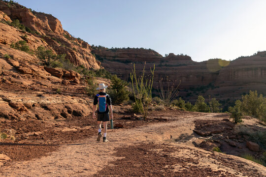Young male hiker walks along a dusty red rock trail