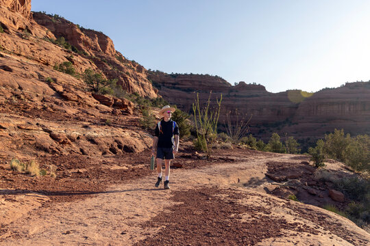 Young man hiking alone on a sunny desert trail
