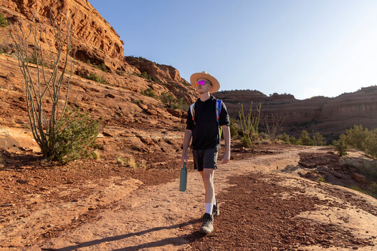 Young man walking on a desert canyon trail