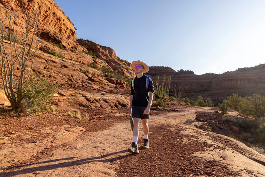 Young man hiking on a sunny red rock trail