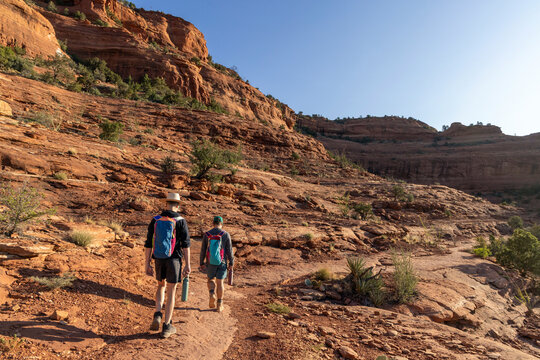 Two men hiking through red rock desert landscape