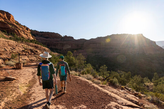 Two friends hiking a desert trail at sunset