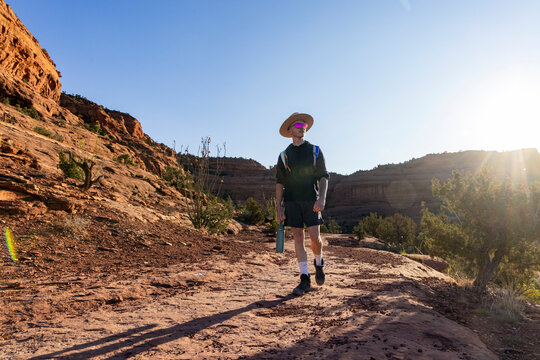 Young man hikes on a sunny desert trail