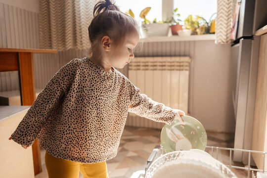 Little girl helps unload dishwasher