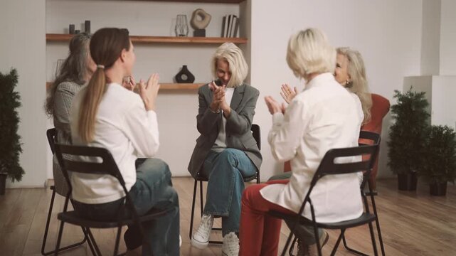 Friendly atmosphere in women group therapy, ladies smiling and applauding. Positive female persons supporting each other and cheering new participant, mutual support group for senior divorced ladies