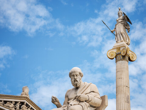 Plato and Athena statues at the Academy of Athens with a partial pediment view, under a bright blue sky, evoking philosophy, heritage, and classical Greece.
