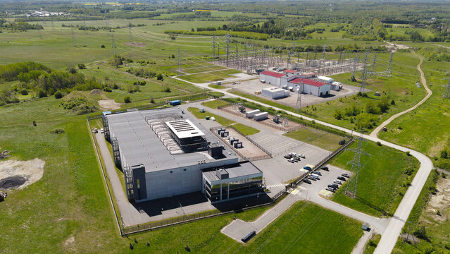 Modern AI data center facility expanding across a green rural landscape, integrating high voltage electrical substation infrastructure for substantial power supply and data processing