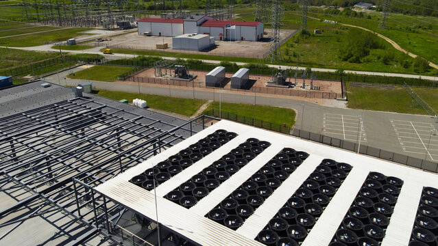 Aerial view of a data center rooftop with large cooling fans and adjacent electrical substation, highlighting power infrastructure, HVAC climate control and industrial scale operations