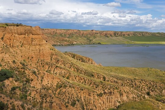 Ein felsiger Canyon, der sich entlang eines Sees erstreckt, unter einem &uuml;berwiegend blauen Himmel mit Wolken, Barrancas de Buruj&oacute;n, Burujon, r&iacute;o Tajo, Fluss Tajo, embalse de Castrej&oacute;n, Stausee de Castrejon, Toledo, Kastilien-La Mancha, Spanien