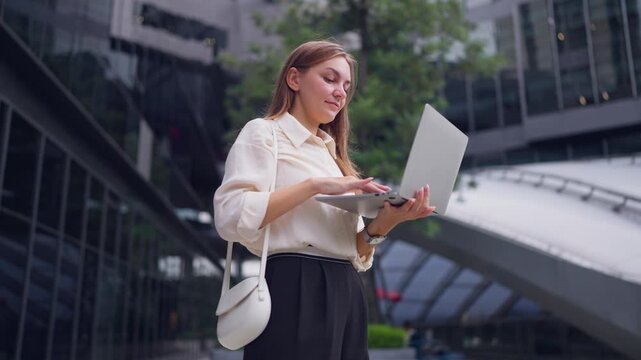 Caucasian young businesswoman using laptop device outside the office. 