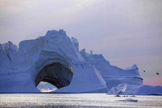 Kayaker in front of huge iceberg, ice cave, midnight sun, Ilulissat, Disko Bay, Denmark, Greenland