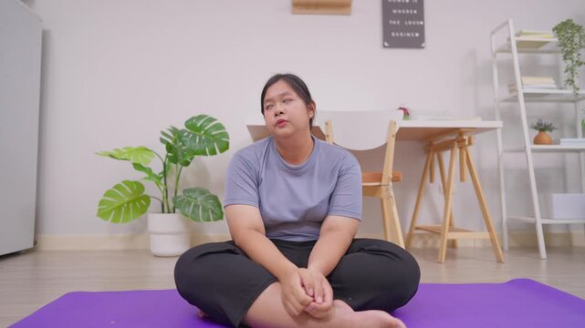 Asian plus-size woman experiencing body aches while exercising in house. 