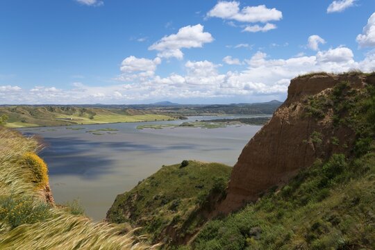 Ein weiter Blick auf einen See inmitten einer h&uuml;geligen Landschaft unter einem blauen, wolkigen Himmel, Barrancas de Buruj&oacute;n, Burujon, r&iacute;o Tajo, Fluss Tajo, embalse de Castrej&oacute;n, Stausee de Castrejon, Toledo, Kastilien-La Mancha, Spanien