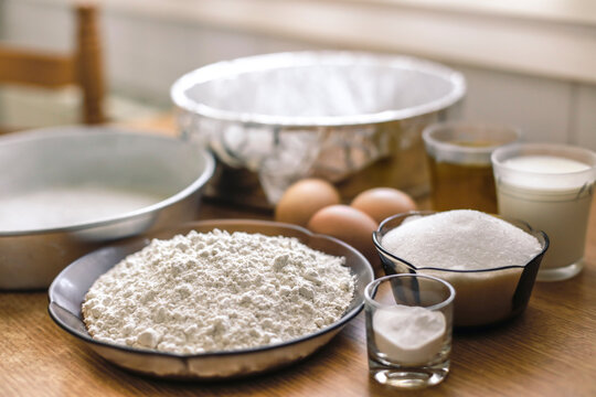 Ingredients for a cake, wheat flower, sugar, milk and eggs on pastry board