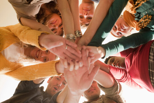 Germany, Leipzig, Group of university students putting hands together, low angle view