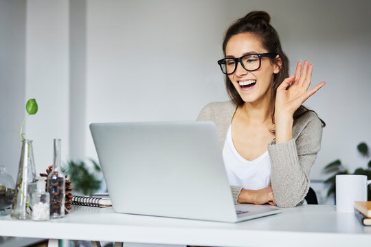 Young woman laughing during video chat at desk