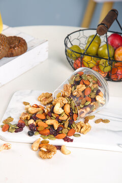 Mixed nuts dried fruit seeds spilling from jar marble counter healthy snack food nutrition