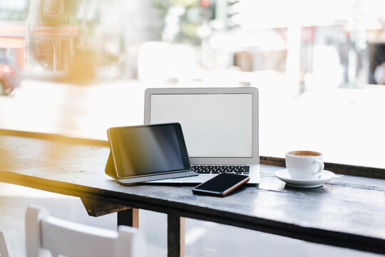 Mobile devices in cafe by cup of coffee