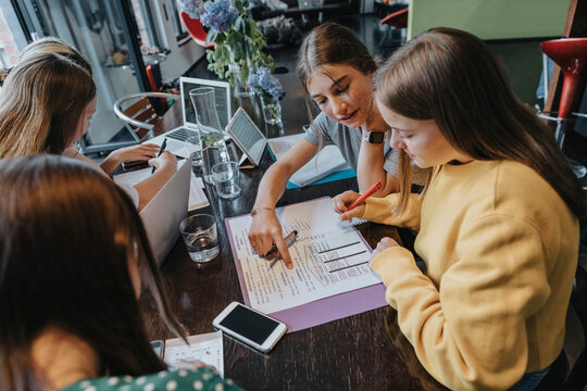 Teenage girls studying and learning from home, assisting eachother