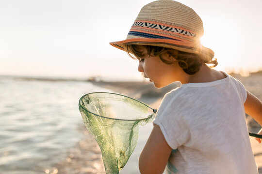 Spain, Menorca, little girl with a dip net on the beach