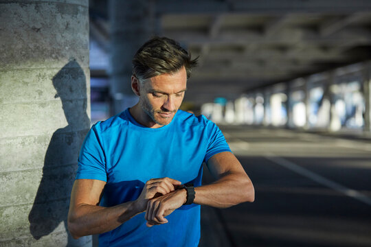 Athlete in the city looking on smartwatch