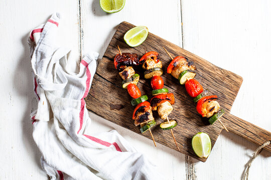 Grill skewers with grilled chicken, tomato, bell pepper and zucchini on chopping board