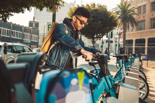 Stylish young man on the street with rental bike
