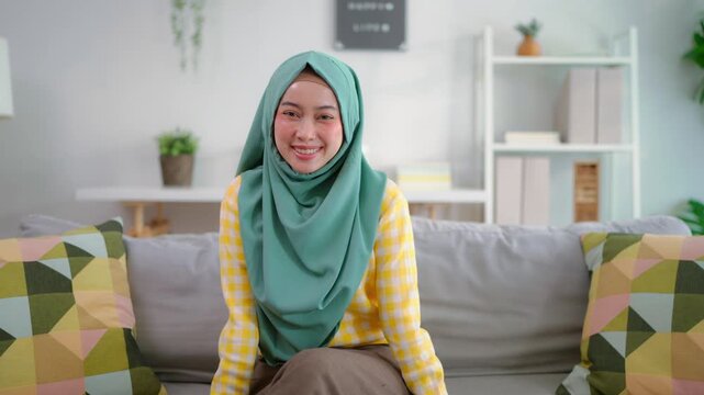 Portrait of Asian Muslim woman sitting on sofa in living room at home. 
