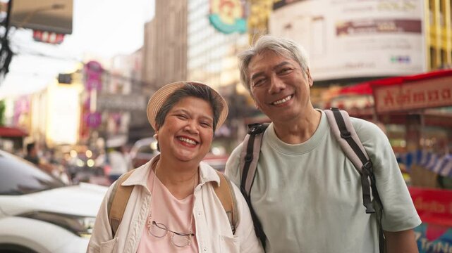 Portrait of Asian senior couple smiling while exploring city outdoors. 