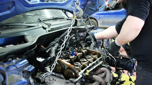 Specialist reviews reliability of chain and inspects engine. Technician in gloves performs comprehensive repair of system standing in front of car