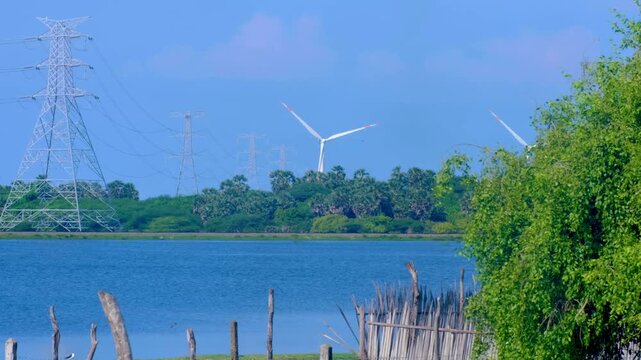 Renewable energy wind turbine on wind farm turning in distance overlooking lake in rural landscape of Mannar Island in Northern Province Sri Lanka