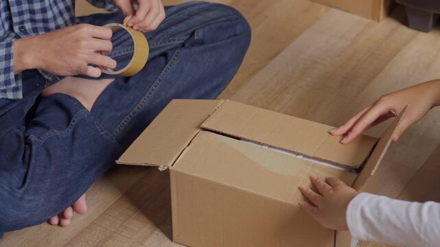 Close-up of couple hands collaborating to organize clothes and secure shipping parcel