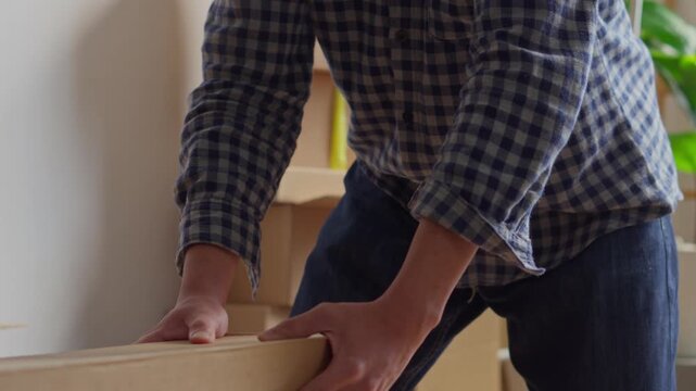 Close-up shot of hands coordinating to pick up and move heavy box during relocation