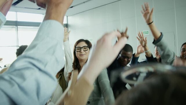 Group of diverse business professionals demonstrate strong teamwork and unity. They huddle, hands together, then cheer triumphantly, symbolizing successful collaboration and achievement.