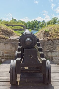 Historic cannon mounted on wooden carriage at the well-preserved Kuressaare Episcopal Castle (Kuressaare Castle) in summer with clouds in the sky, Saaremaa, Estonia, Europe.