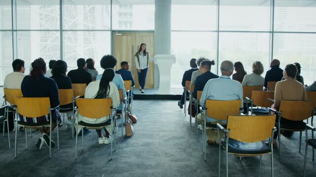 A speaker delivers an engaging presentation to a diverse group of attendees. This corporate conference event fosters learning and professional development for various industries and individuals.