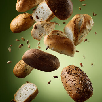 Schwebende Brotauswahl mit Br&ouml;tchen und Brotlaiben vor gr&uuml;nem Hintergrund. Kreative Food-Fotografie, frische Backwaren, B&auml;ckerei-Konzept mit Copyspace und Dynamik.