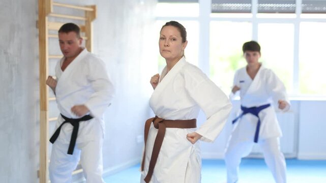 Three athletes have taken starting position and studying and repeating sequence of punches and painful techniques in karate kata technique. Oriental martial arts, training and obtaining black belt