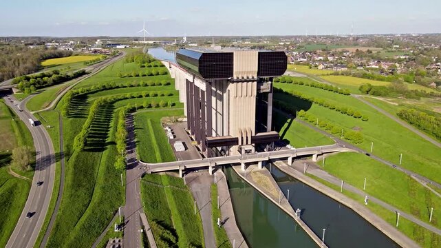 Vertical orbital drone movement around canal lift tower showing structural joints and hydraulic components. Access platforms and sensors visible on concrete facade with close inspection framing.