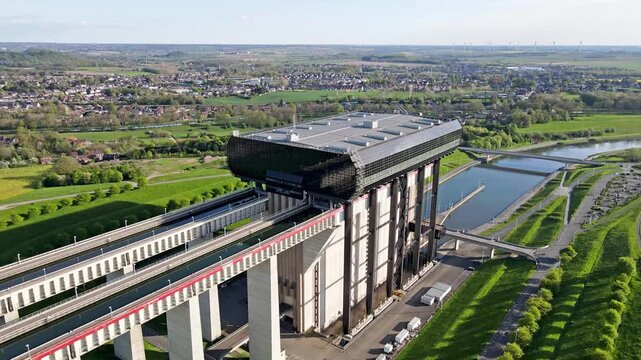 Aerial drone close framing on canal lift exterior cladding and support beams with inspection walkway and maintenance vehicle. Safety railings and crisp shadows with engineered symmetry detail. Lift