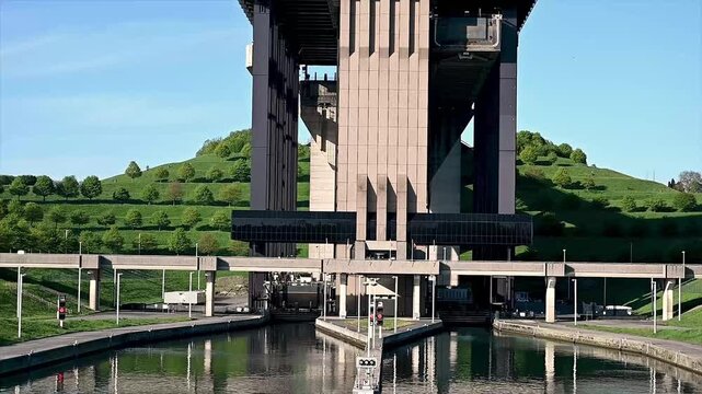 Static close-up view of canal boat lift lock gates slowly closing after barge has entered the caisson chamber. Hydraulic mechanism sealing water-tight compartment with concrete walls and steel gate
