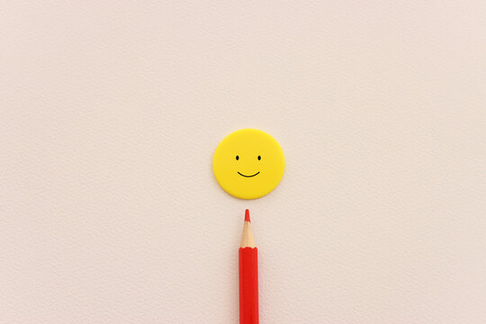 Concept image of satisfaction level. plastic circle with happy face and red pencil