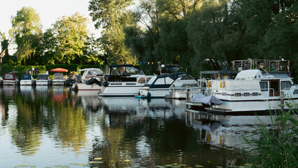 Scenic boat station pier with rented rowing boats and catamarans moored on a calm lake water © Сергей Безрученко
