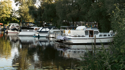 Scenic boat station pier with rented rowing boats and catamarans moored on a calm lake water © Сергей Безрученко