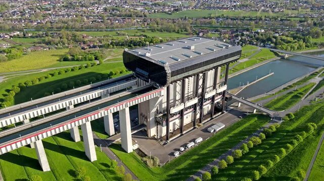 Static aerial timelapse of cargo barge being slowly lifted to the top level inside canal lift caisson. Accelerated vertical ascent showing full lifting sequence with concrete towers and green