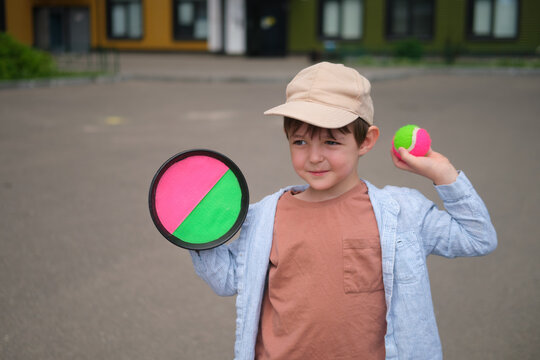 Little boy playing catch with velcro paddle and ball. Child having fun in park during summer. Outdoor activity and active leisure for youngster. Healthy lifestyle and childhood sport.