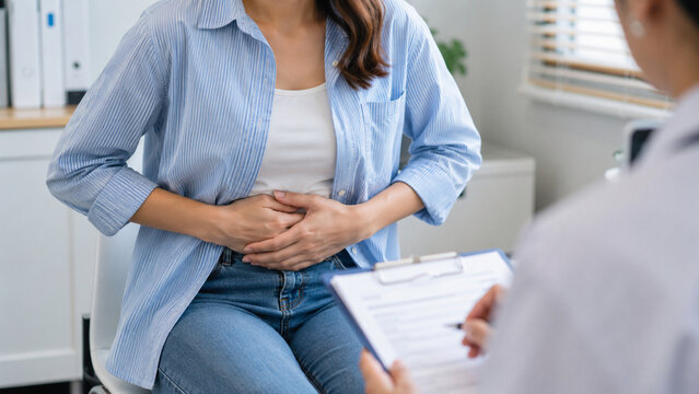 Female patient with abdominal pain consulting doctor in clinic for digestive health diagnosis
